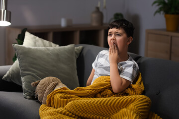 Wall Mural - Cute sleepy little boy with teddy bear yawning on sofa in living room