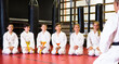 Group of positive preteen children greeting karate coach at sport gym