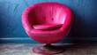 Elegant and vibrant pink velvet swivel chair against a textured dark blue wall in a modern and luxurious interior design setting.