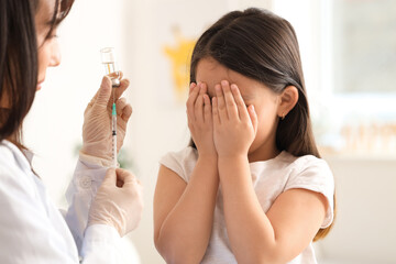 Sticker - Scared little Asian girl receiving vaccine at hospital, closeup