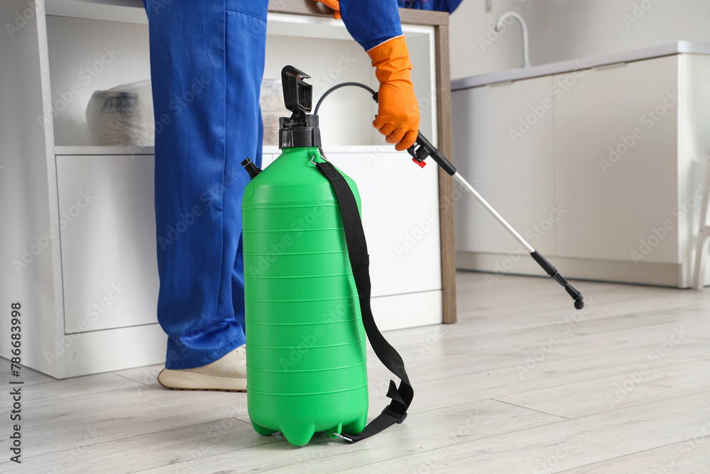 Male worker disinfecting floor in kitchen, closeup