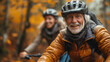 Happy elderly man wearing a cycling helmet and an orange jacket, smiling while riding a bike in the forest during autumn.