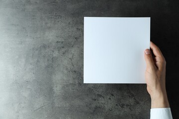 Canvas Print - Man holding blank book at black textured table, top view. Mockup for design