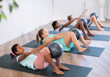 Fototapeta Zwierzęta - Group of multiethnic kids practicing pilates with soft ball on mat in studio