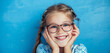 Against a calming blue background, a young girl giggles as she pushes her glasses up on her nose, her eyes sparkling with joy and vitality
