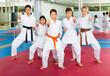 © JackF - Teenager children wearing karate uniform fighters poses in white kimono during group training in gym