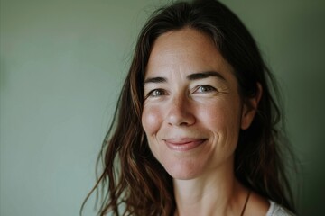 Wall Mural - Portrait of a smiling woman with long brown hair looking at camera