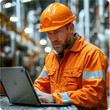 A man in an orange safety suit is working on a laptop