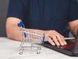 Online shopping concept with miniature shopping cart.