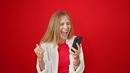 Sticker - Excited young woman with blonde hair reacting to smartphone content against a vibrant red background.