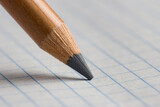 Fototapeta  - The tip of a pencil on a checkered paper in close-up.