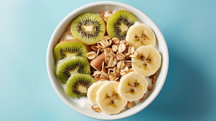 Canvas Print - Healthy fiber rich breakfast option Crunchy honey muesli with fresh banana and kiwi slices in a white bowl on a blue background