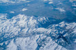 An aerial view from an airplane window of mountains, snow, clouds and bright blue skies. United States