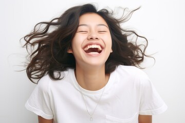 Wall Mural - A beautiful Asian woman with long straight hair  whose skin is tan is wearing an all white shirt, and smiling with a face which is full of happiness in a white room. Generative AI.