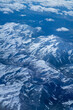 An aerial view from an airplane window of mountains, snow, clouds and bright blue skies. United States