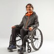 A smiling young woman with a disability sitting in a modern wheelchair against a neutral background.