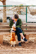 Woman sitting on bench at dog park petting dog