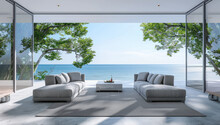 A Large Modern Living Room With Grey Sofas And White Walls, Overlooking The Sea In An Island. The Windows Show Trees On One Side Of The Wall And Ocean In Front.