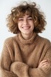 Portrait of a smiling young woman with curly hair, wearing a warm brown sweater, symbolic of comfort and happiness.