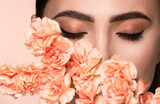 Fototapeta Tęcza - Closeup studio beauty portrait of young beautiful woman framed with peach flowers.