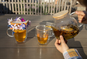 children's hands with transparent teapot from which he pours tea into two glass cups. bread toast with spring flowers. Breakfast for mom on Mother's Day. good morning, floral fantasies, relaxing