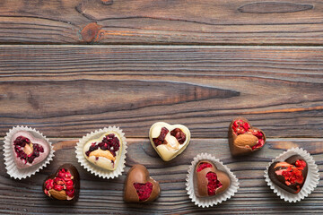 Wall Mural - chocolate sweets in the form of a heart with fruits and nuts on a colored background. top view with space for text, holiday concept