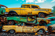 Old, rusty, yellow and green cars piled up in a scrapyard. Damaged cars waiting in a scrapyard to be recycled or used for spare part.