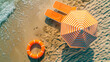 Top view of fine golden sand, a chaise longue and a striped orange beach umbrella, an inflatable rubber swimming circle.