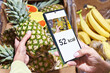 Checking calories on pineapple in store with smartphone