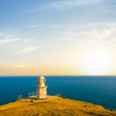 Wall Mural - lighthouse on a marine cape at the sunset