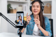 Selective focus phone in host channel of young beautiful Asian in creative broadcaster talking online explaining to promote marketing or consultant in daily life with listener at studio. Stratagem.