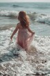 © Fotograf - A young girl in a pink dress walking into the ocean. Ideal for summer vacation concepts