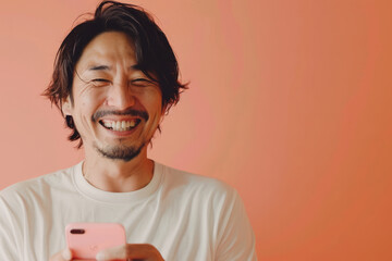 Wall Mural - A Japanese man smiles brightly while recommending a vibrant mobile app on a peach background, his positive energy contagious.