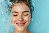 Fototapeta Mapy - healthy moisturized face skin. skincare and hydration concept. smiling woman with eyes closed and water splash around the face on light blue background