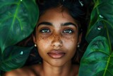 Fototapeta  - Top view of a content indian girl surrounded by lush green leaves