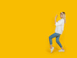 Doing stop gesture, side full length body view 20s blonde caucasian girl doing stop gesture. Showing open palm aside copy space. Personal space sign, say no concept idea image. Yellow background.