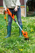 String trimmer. Woman is trimming grass in garden. Lawn care in spring