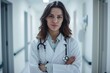 © Nikolay - A portrait of a female doctor standing in medical corridor with stethoscope.