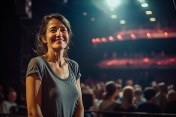 Wall Mural - Portrait of a tender woman in her 50s dressed in a casual t-shirt while standing against lively concert stage