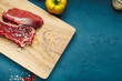 Two slices of raw meat on a cutting board in the kitchen, prepared to make dinner. Free space for text for recipes, and home cooking lessons. Fresh meat to make a stake.