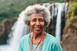 Portrait of a blissful afro-american woman in her 80s dressed in a casual t-shirt while standing against backdrop of a spectacular waterfall