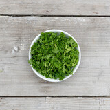 Fototapeta Lawenda - sliced ​​fresh curly parsley on a light wooden background