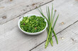 White bowl with sliced ​​chives on a light wooden background