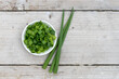 White bowl with sliced ​​spring onions on a light wooden background