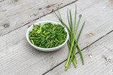 Fototapeta Lawenda - White bowl with sliced ​​chives on a light wooden background