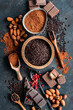 Schokolade, Nüsse und rote Pfefferkörner auf einem rustikalen schwarzen Hintergrund. Flatlay.