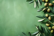 Photorealistic green olives, olive leaves, and branches lying on a green background. Top view. Food banner with copy space.