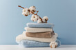 Stack of delicate colored cotton towels with cotton buds on blue background