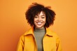 © Markus Schröder - Portrait of a glad afro-american woman in her 20s dressed in a water-resistant gilet on soft orange background