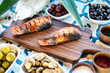 Wooden Cutting Board With Fish and Bowls of Olives